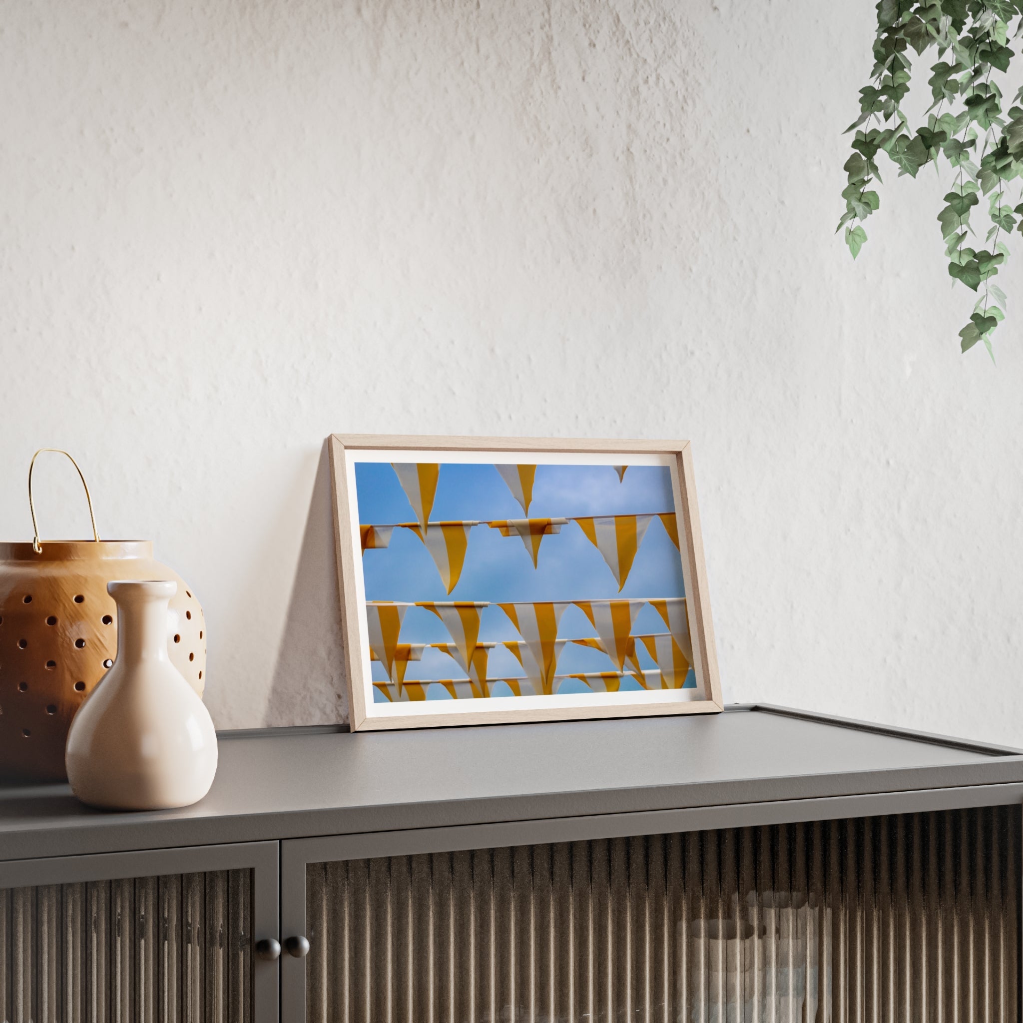 Framed artwork on a shelf with decorative items and a plant in the background