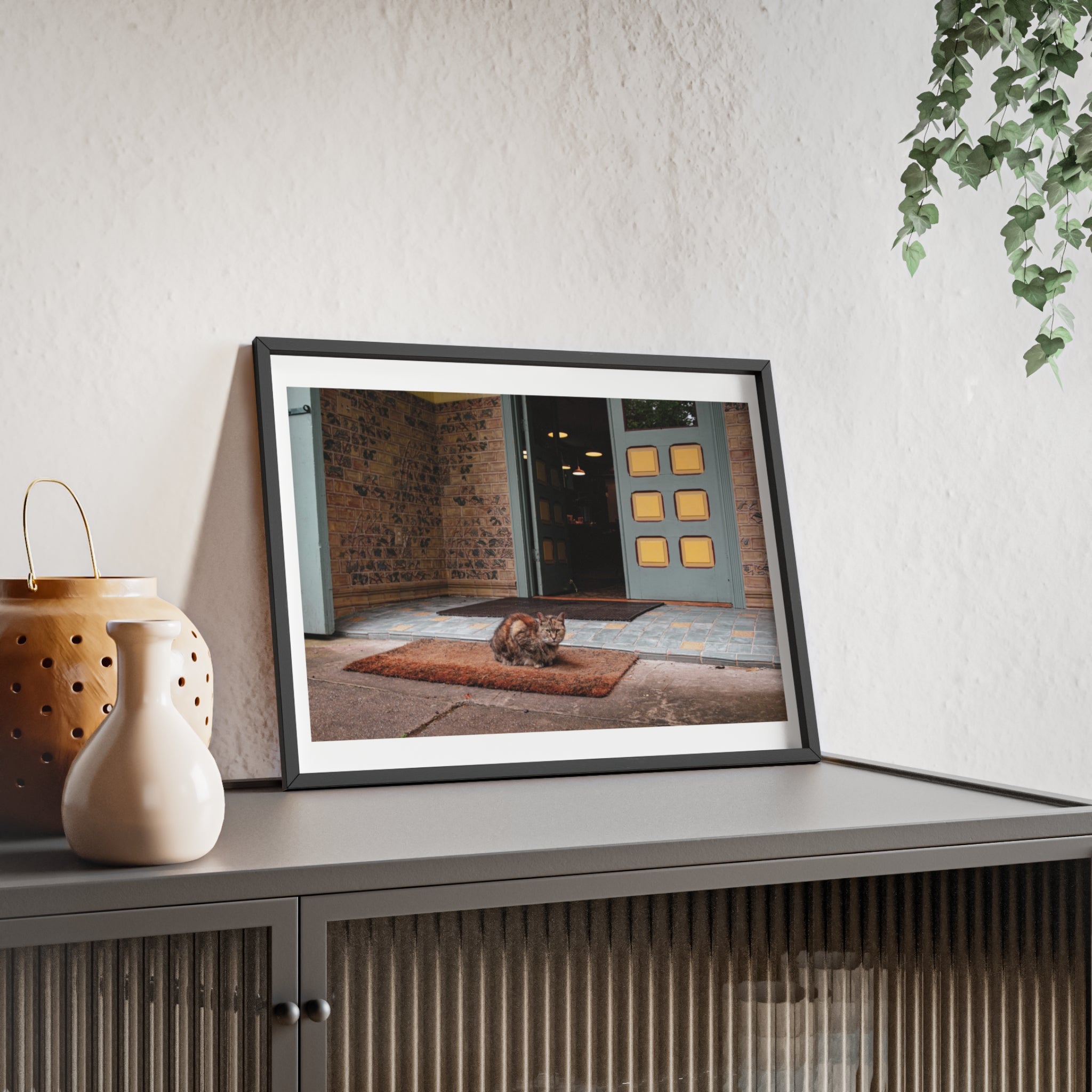 Framed picture on a shelf with decorative items and a plant in the background