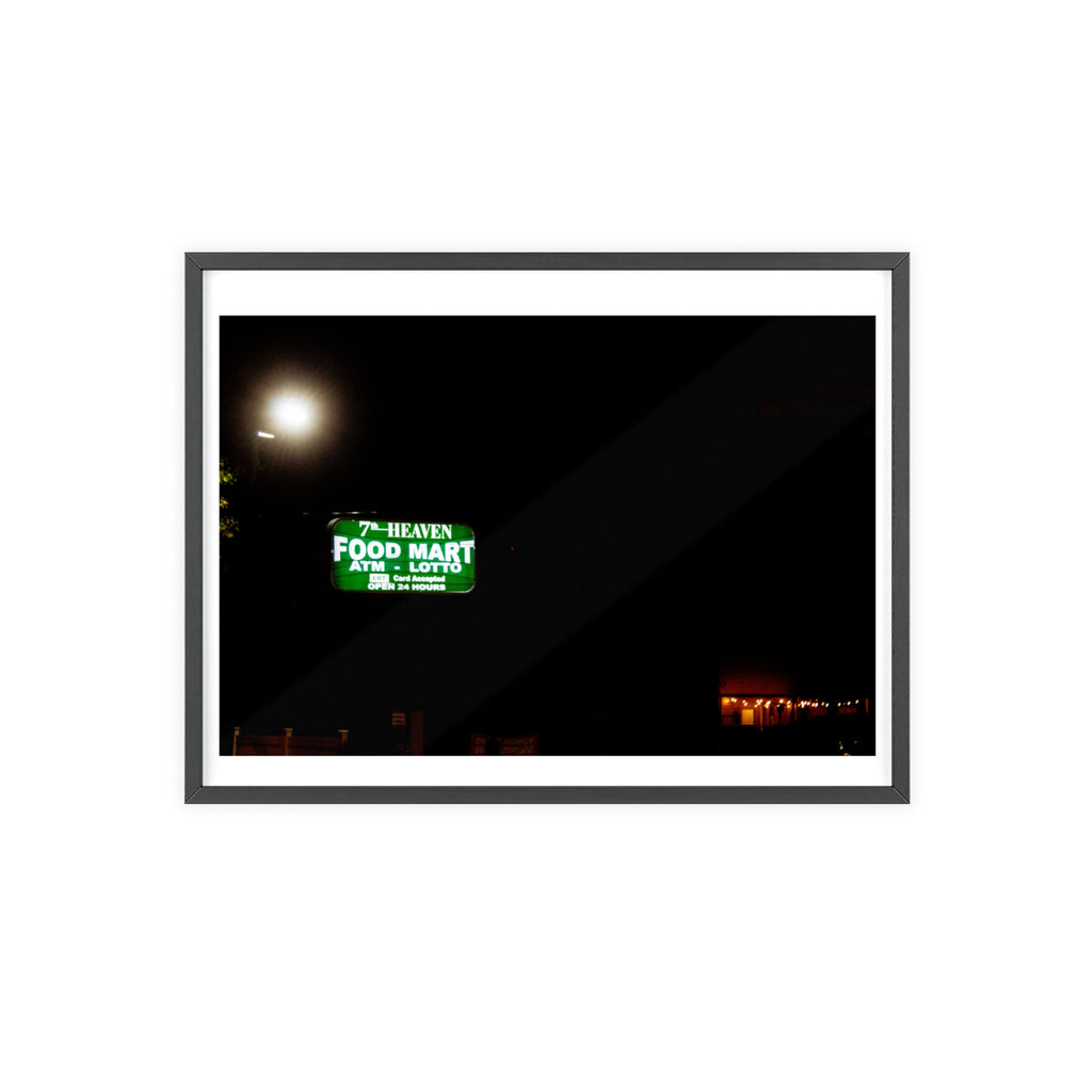 Framed photograph of a street sign at night with a bright light source.