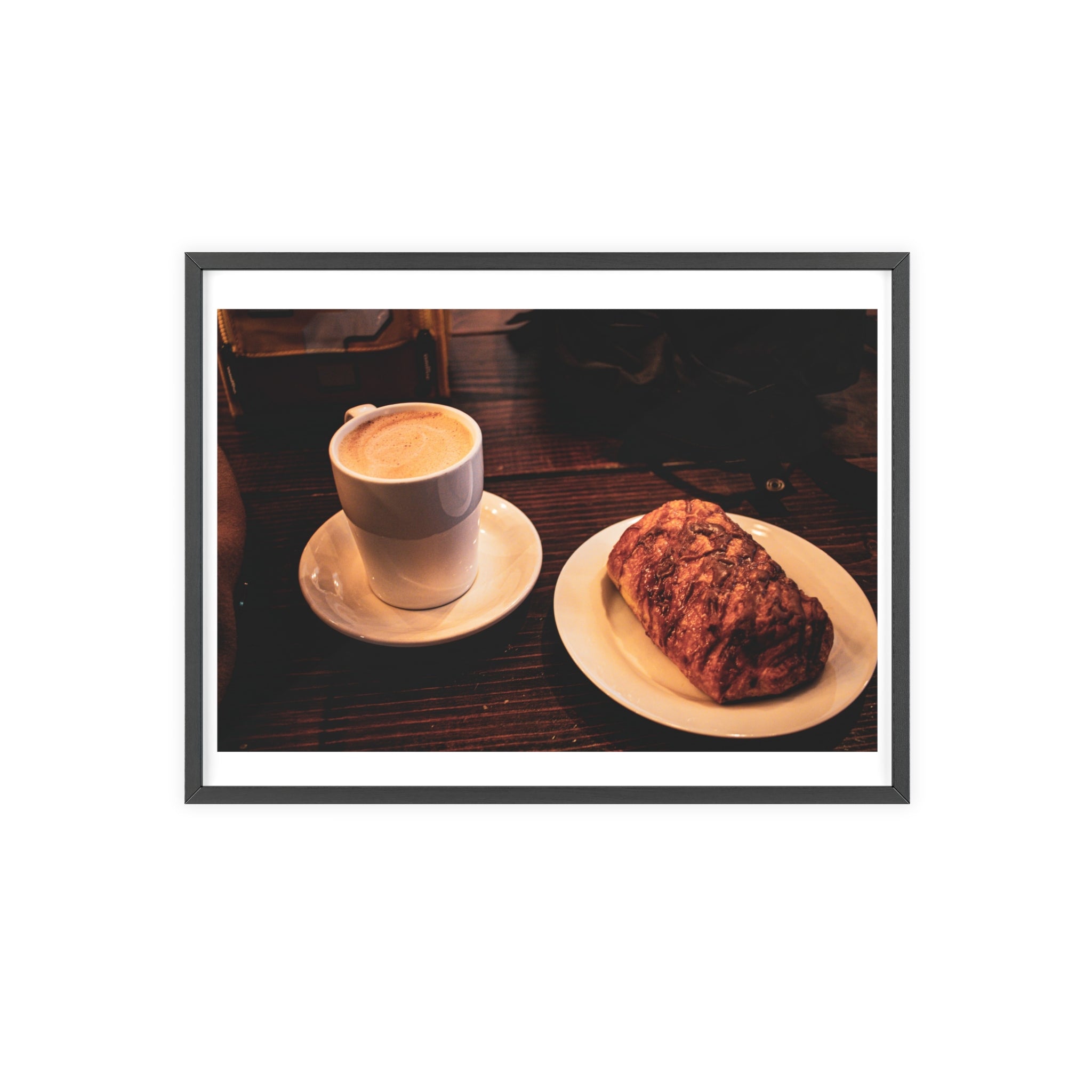 Cappuccino in a white cup and a pastry on a white plate on a wooden table.