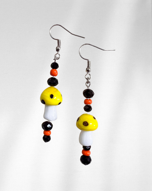 Pair of beaded earrings with yellow, black, and orange beads on a white background