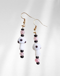 Pair of beaded earrings with white glass mushroom charms, white, pink, and black beads on a light gray background