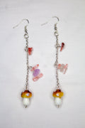 Pair of earrings with colorful mushroom-shaped beads on a light gray background