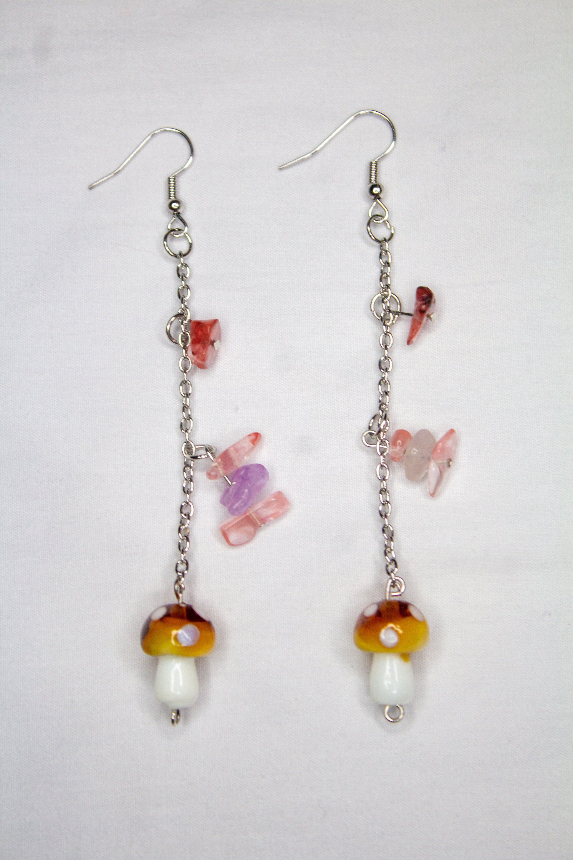 Pair of earrings with colorful mushroom-shaped beads on a light gray background