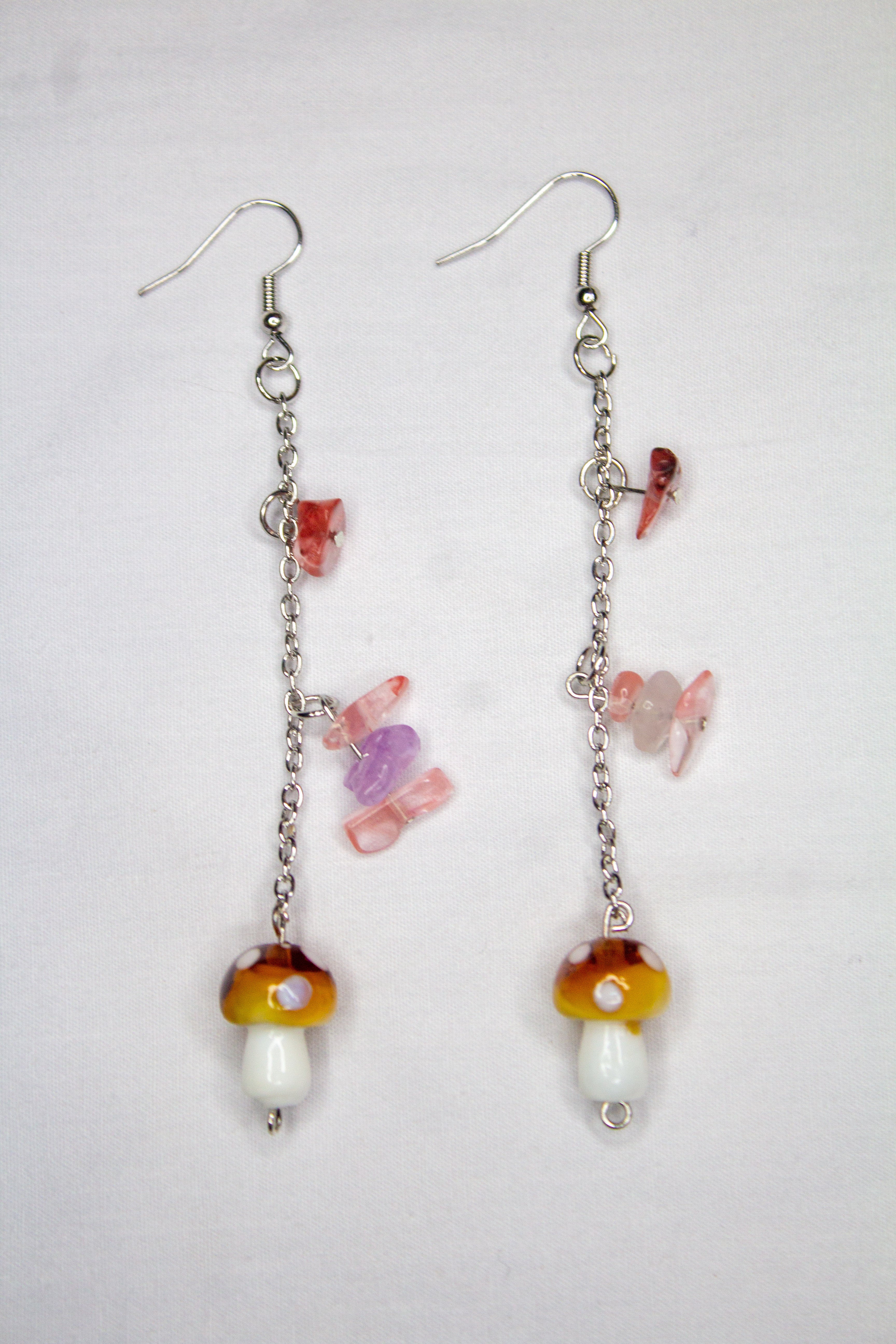 Pair of earrings with colorful mushroom-shaped beads on a light gray background