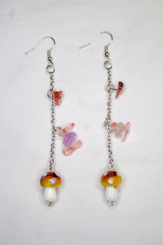 Pair of earrings with colorful mushroom-shaped beads on a light gray background